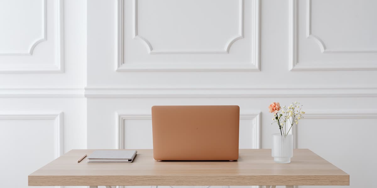 Aufgeräumter Schreibtisch mit Laptop und Notizbuch