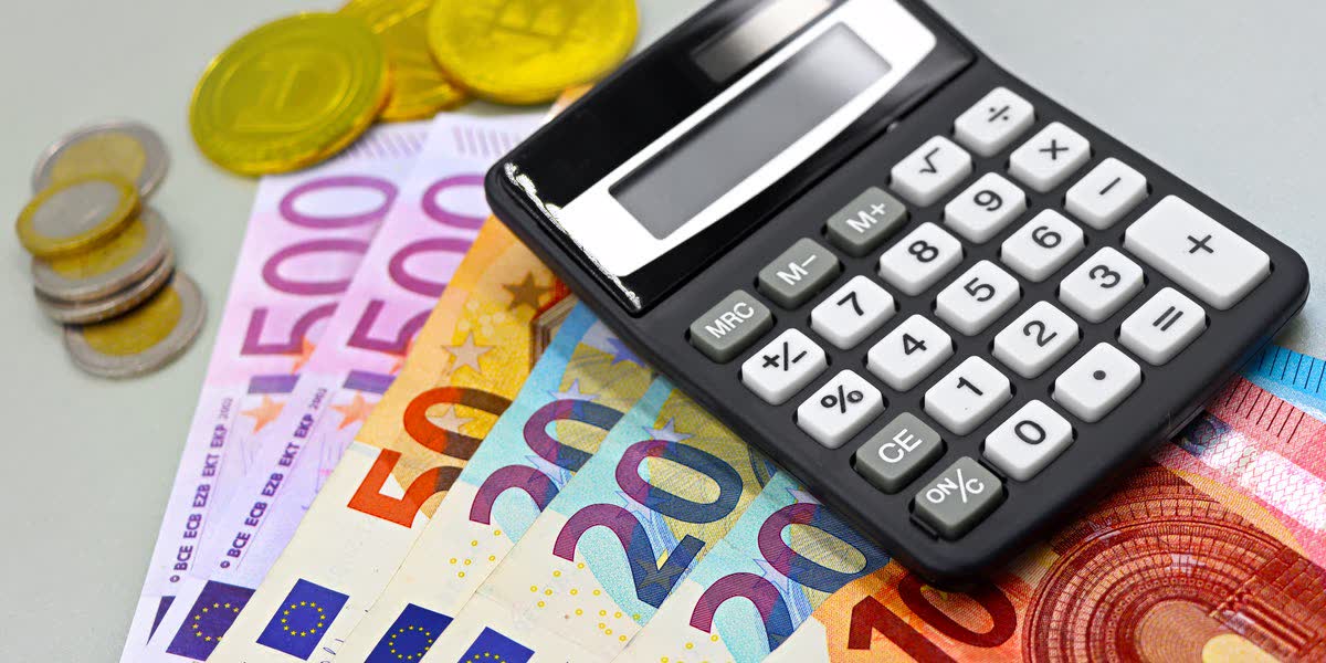 Euro-Banknoten, Münzen und ein Taschenrechner auf einem Tisch